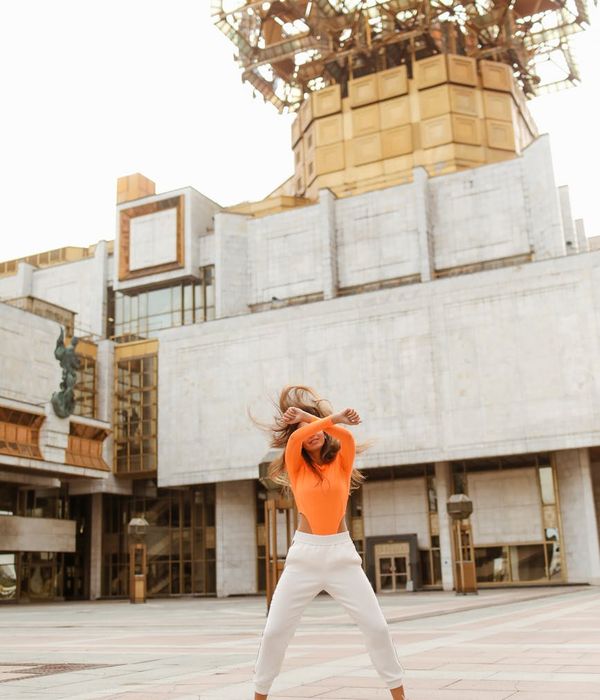 Woman performing a dynamic stretching movement in a bright, modern space.